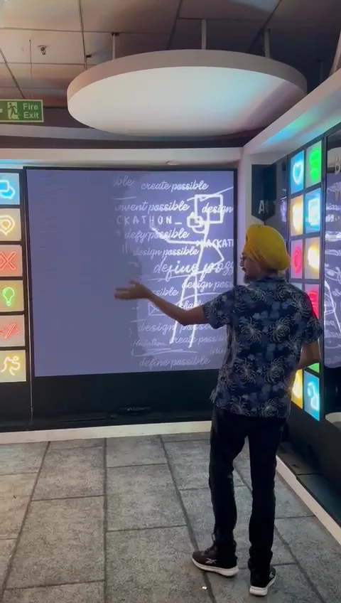 The installed screen in the centre, the chalk figure mid-pose, a column of lit colour tiles on the wall beside it